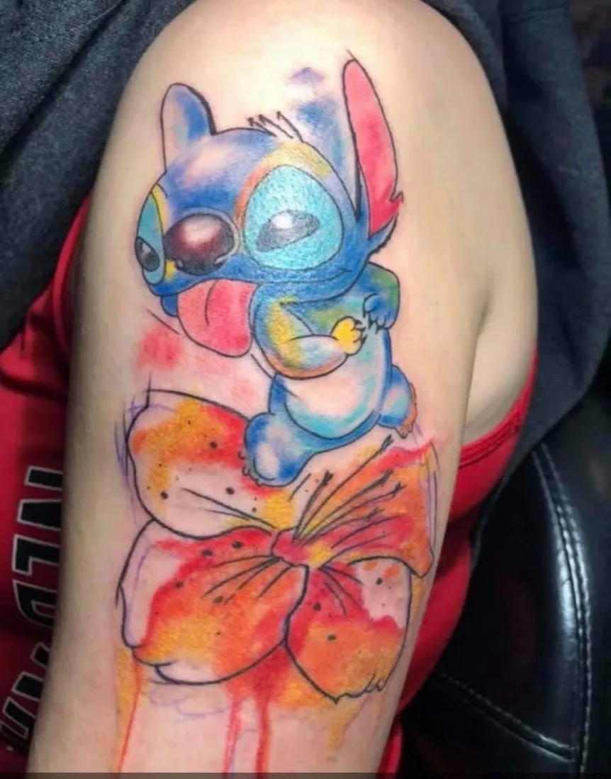 Watercolor-style arm tattoo of a cartoon character on a flower
