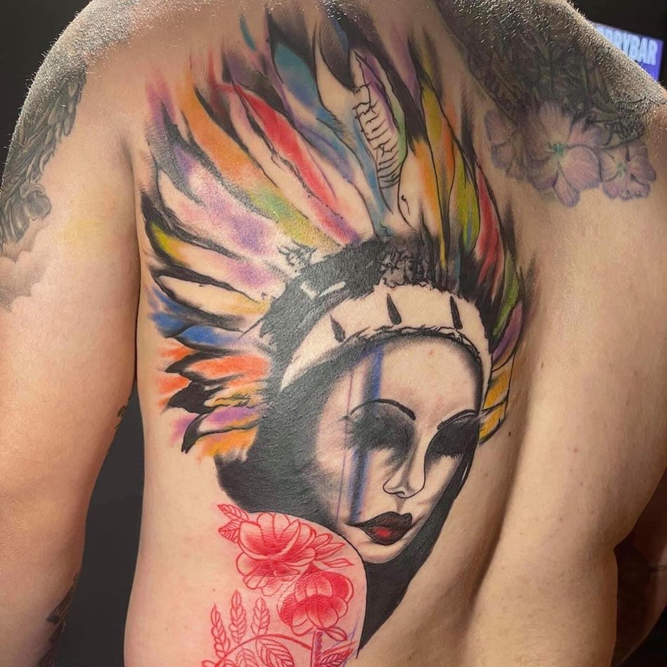 Color back piece: a woman's face under a rainbow feathered headdress