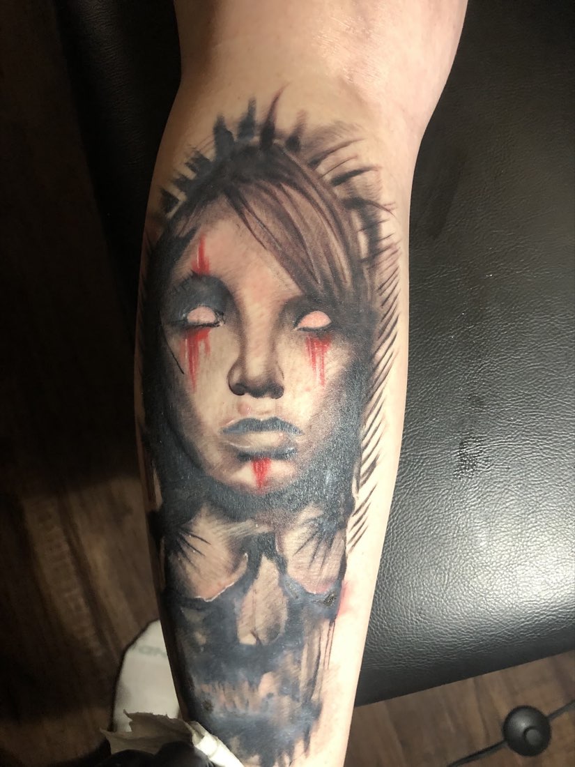 Black and grey calf tattoo of a woman's face with red tears
