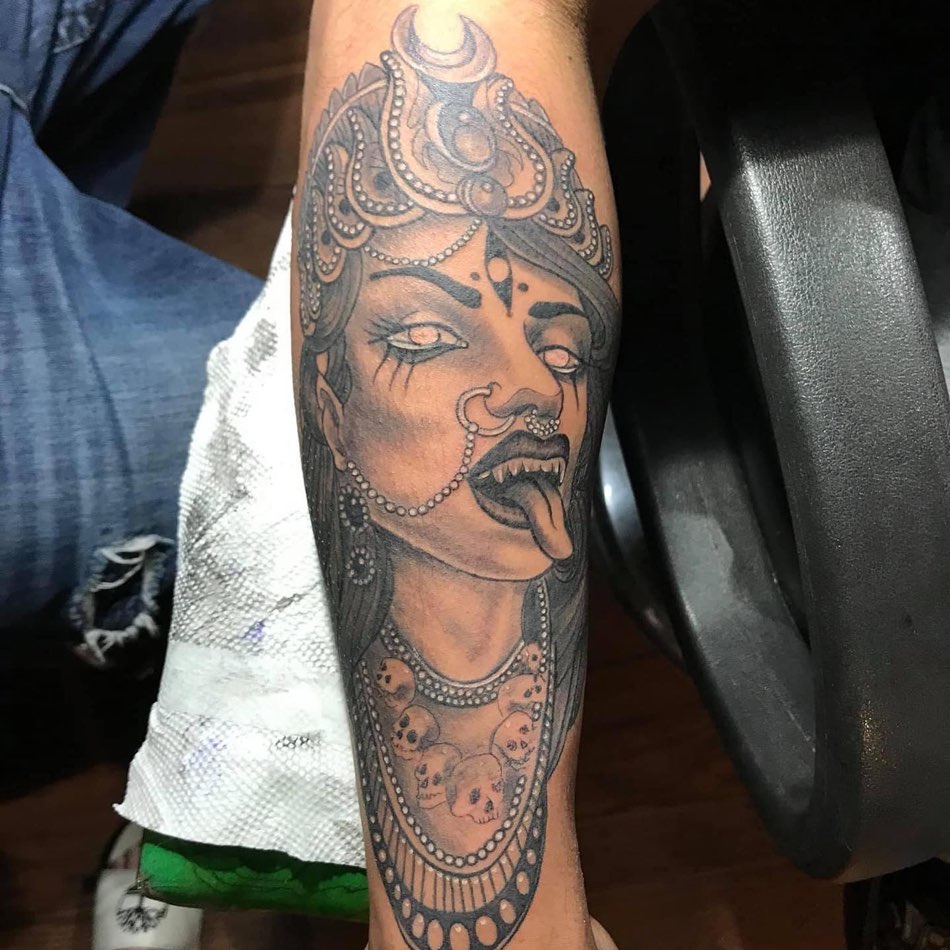 Black and grey forearm tattoo of a goddess with a crown and a skull necklace