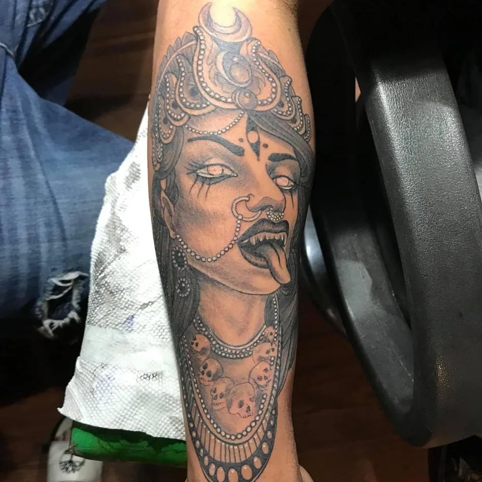 Black and grey forearm tattoo of a goddess with a crown and a skull necklace