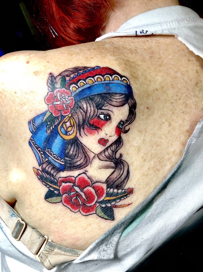 Shoulder tattoo of a woman in a blue headscarf with red roses